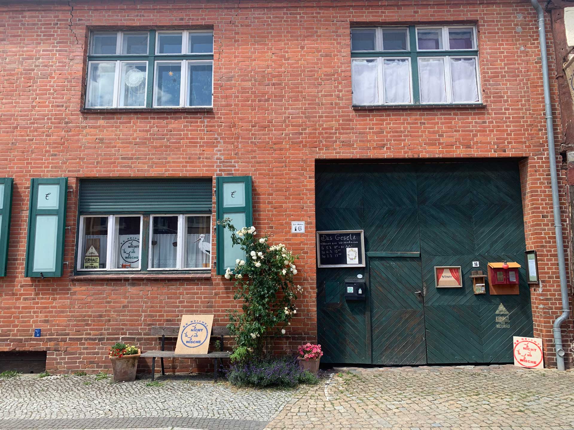 Ein Backsteinhaus in der Altstadt der Hansestadt Werben mit mehreren Schildern mit der Aufschrift "Es reicht! Nicht in die Wische"